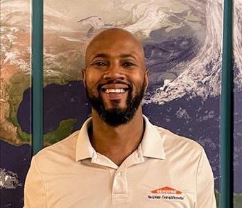 Male employee with black beard posed in front of SERVPRO World Image