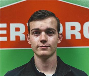 Male employee with dark hair posing in front of SERVPRO logo 
